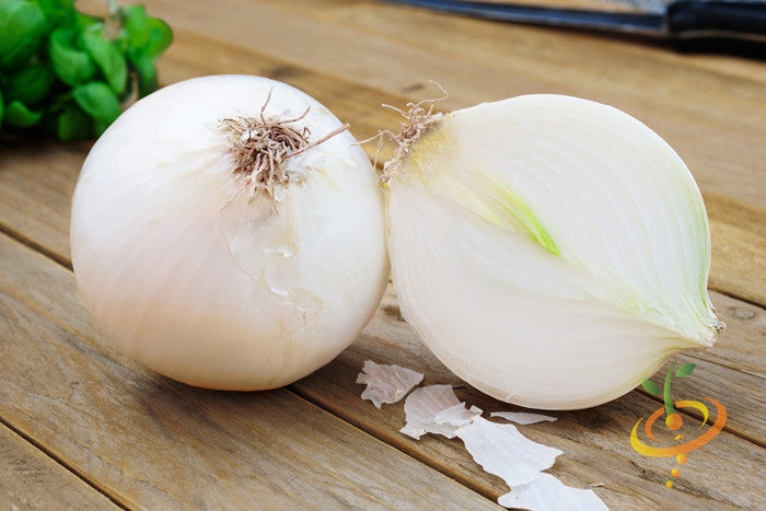 Spanish Sweet White Onion whole and halved on wooden surface with knife in background