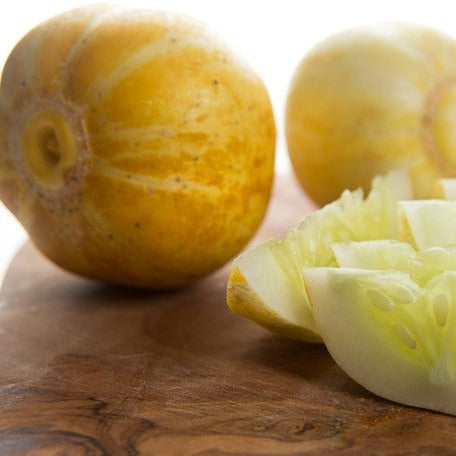 Lemon cucumber whole and sliced on wooden surface showing yellow skin and pale green interior