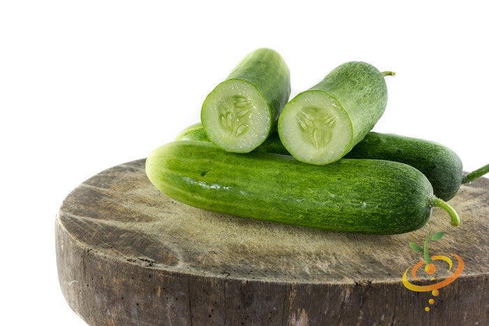 Marketer cucumbers whole and sliced on wooden cutting board