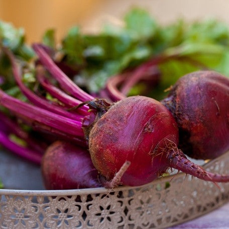 Fresh deep-red Boltardy Beet roots with leafy green tops in a decorative metal tray