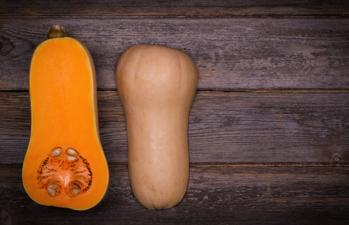 Whole and halved butternut winter squash on wooden background